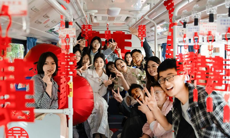 Newlyweds Tang Shanqing and Hu Qiankun pose for a photo with their family members and friends on a wedding bus in Suqian, east China's Jiangsu Province, Oct. 28, 2023. (Xinhua)