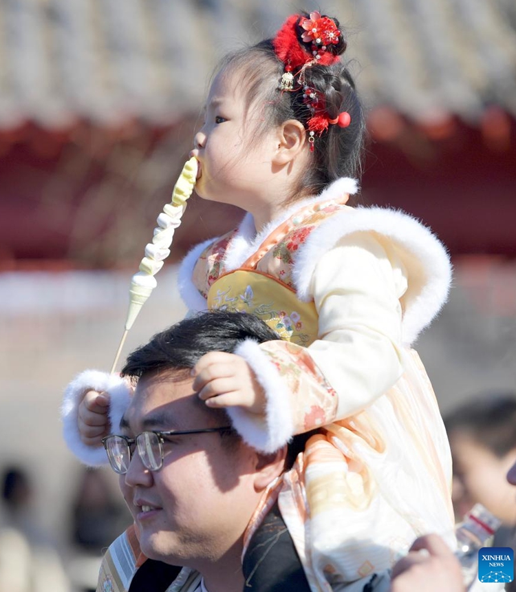 A child enjoys snacks in Jingxing County, Shijiazhuang City, north China's Hebei Province, Feb. 11, 2024. Many people choose to wear traditional Chinese costumes to celebrate the Chinese New Year. (Photo by Zhang Xiaofeng/Xinhua)