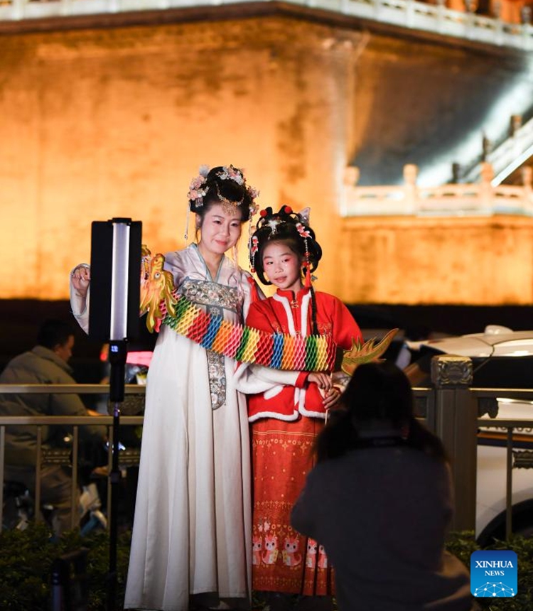 Tourists wearing traditional costumes pose for photos at the Bell Tower scenic spot in Xi'an, northwest China's Shaanxi Province, Feb. 13, 2024. In addition to following traditional customs, more and more Chinese People choose to enrich their life by spending the Spring Festival holiday in diversified and original ways. (Photo: Xinhua)