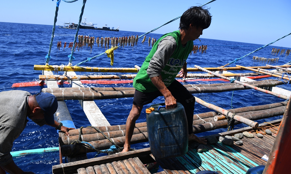 This photo taken on February 15, 2024 shows Filipino fishermen loading plastic containers with free fuel from the Philippine Bureau of Fisheries and Aquatic Resources (BFAR) ship (background) near the Huangyan Dao in the South China Sea. Photo: AFP