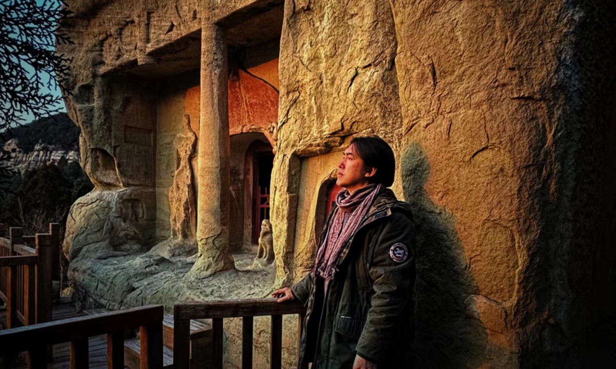 Artist Zhang Jinfeng poses for a photo in front of the Tianlong Mountain Grottoes.Photo:Cao Siqi/Global Times 