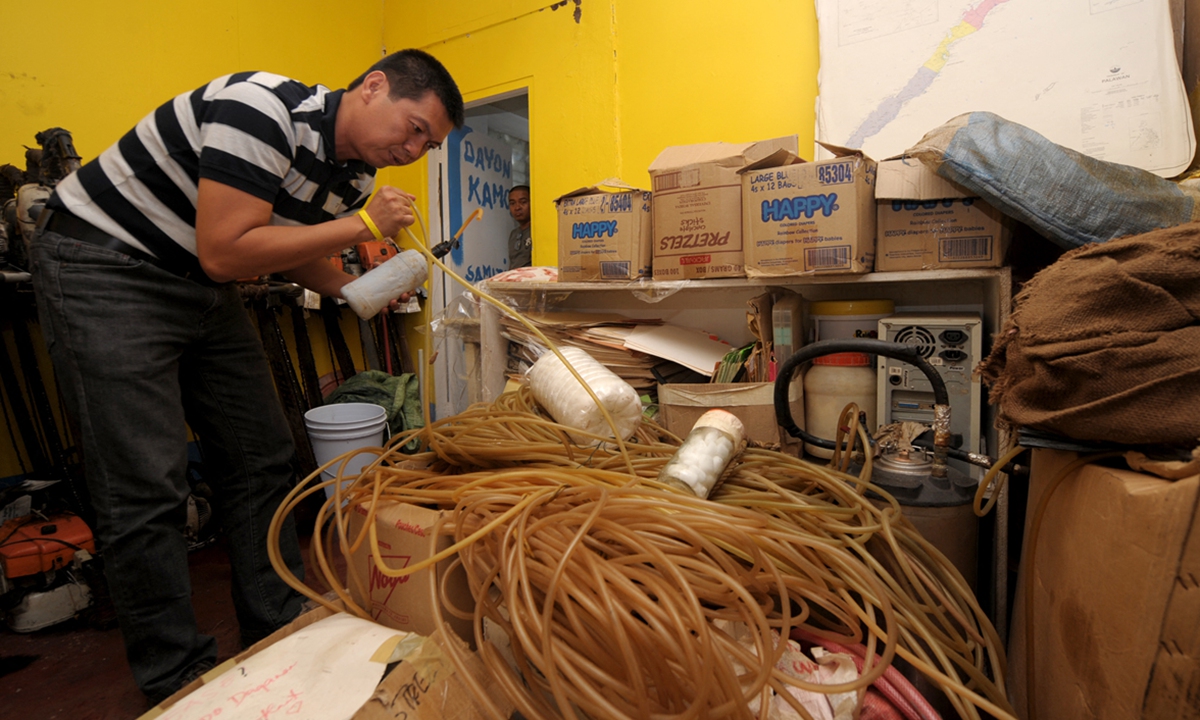 A Philippine environmentalist shows confiscated cyanide bottles and hoses used for cyanide fishing in Puerto Princesa, the Philippines, on February 16, 2011. Photo: AFP