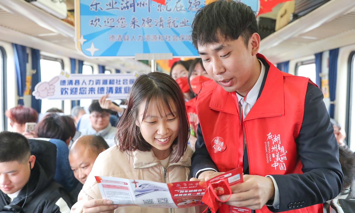 A staff member of the local human resources and social security department in Deqing county, East China's Zhejiang Province offers information to tourists on a train on February 26, 2024. China is shoring up efforts to implement measures to enhance the effectiveness of policies aimed at strengthening employment. 
Photo: VCG
