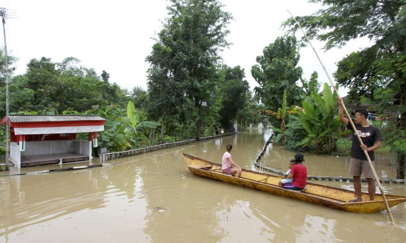 People ride a wooden boat on floodwater after heavy rain and overflow of Bengawan Solo River at Pandak village in Sragen district, Central Java, Indonesia, on March 10, 2024. (Photo by Bram Selo/Xinhua)
