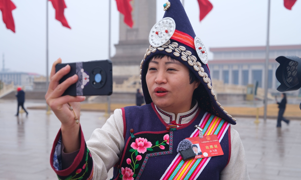 A deputy to the National People's Congress (NPC) livestreams to her colleagues back in Southwest China's Yunnan Province, amid the opening of the annual session of the NPC, the country's top legislature, outside the Great Hall of the People in Beijing on March 5, 2024. China has set a growth target of around 5 percent for its economy in 2024, per the Government Work Report. Photo: VCG