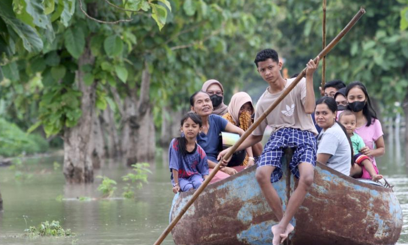 People ride a wooden boat on floodwater after heavy rain and overflow of Bengawan Solo River at Pandak village in Sragen district, Central Java, Indonesia, on March 10, 2024. (Photo by Bram Selo/Xinhua)