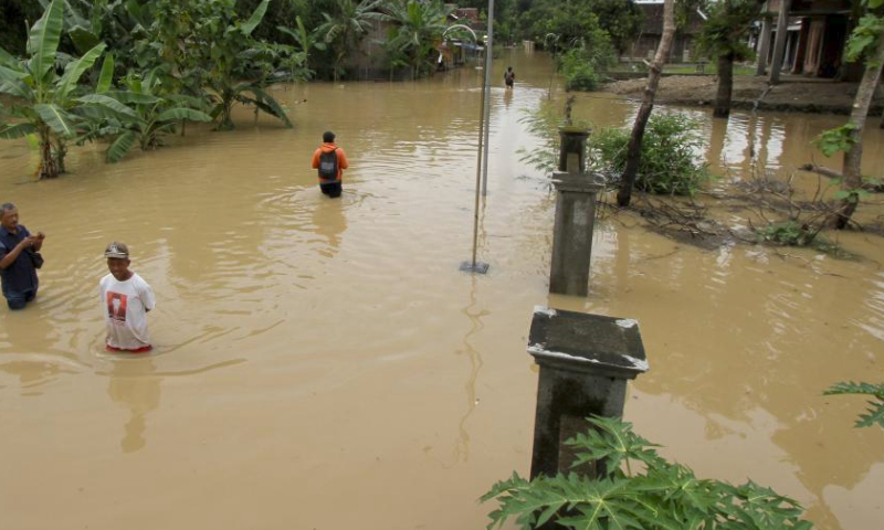 People wade through floodwater after heavy rain and overflow of Bengawan Solo River at Pandak village in Sragen district, Central Java, Indonesia, on March 10, 2024. (Photo by Bram Selo/Xinhua)