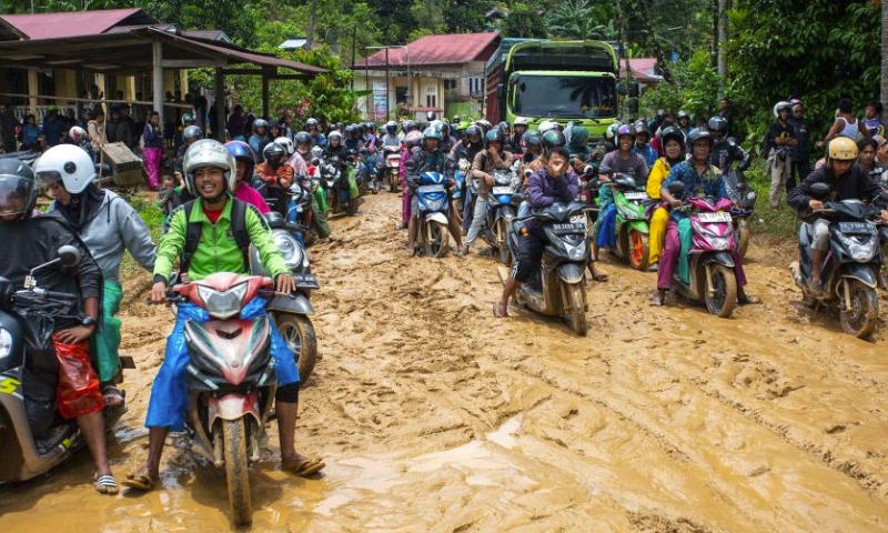 People ride motorbikes on a muddy road after heavy rains in Pesisir Selatan in West Sumatra, Indonesia, March 9, 2024. (Photo by Andri Mardiansyah/Xinhua)