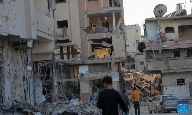 People walk past destroyed buildings in the southern Gaza Strip city of Khan Younis, on March 6, 2024. The Palestinian death toll from ongoing Israeli attacks on the Gaza Strip has risen to 30,717 with 72,156 others wounded, the Hamas-run Health Ministry said in a press statement on Wednesday.(Photo: Xinhua)