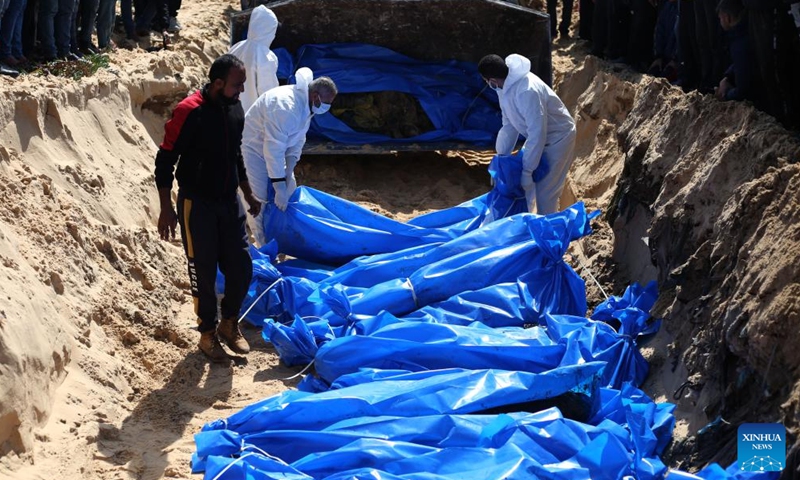 Palestinian workers bury bodies at a grave for victims killed in the Hamas-Israel conflict in the southern Gaza Strip city of Rafah, on March 7, 2024. The Palestinian death toll in the Gaza Strip has risen to 30,800 since the outbreak of the Israel-Hamas conflict on Oct. 7, 2023, the Hamas-run Health Ministry said in a press statement on Thursday.(Photo: Xinhua)