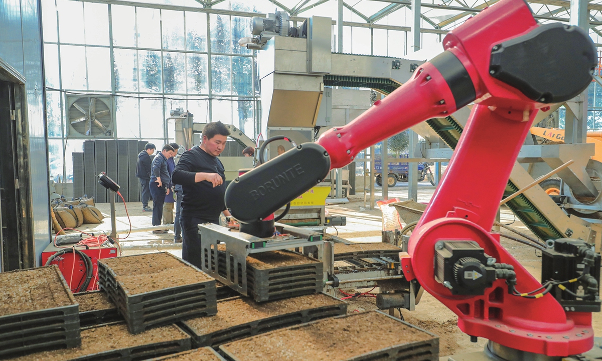 Members of a cooperative in Xinyang city, Central China's Henan Province, operate a robot for intelligent rice-planting on March 10, 2024. The cooperative introduced a new high-tech robot intelligent seeding technology this year, which achieves precision sowing of rice with high speed, but also saves labor and improves production efficiency. Photo: cnsphoto