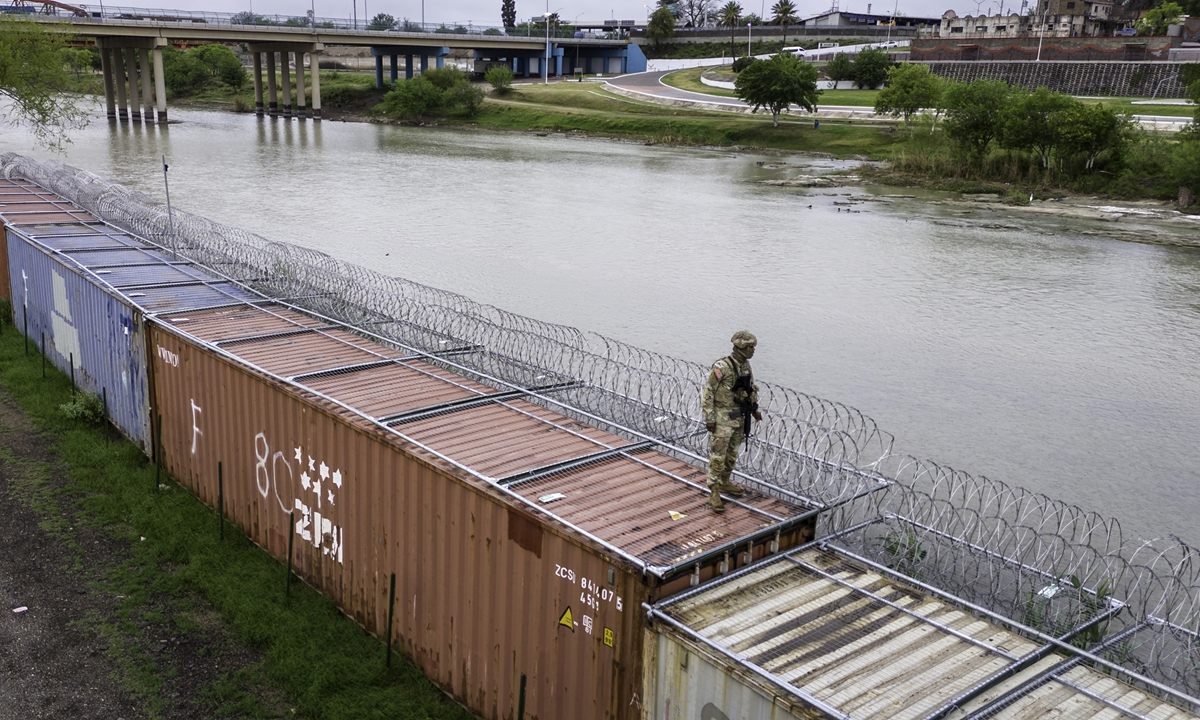 In an aerial view, a Texas National Guard soldier stands atop a barrier of shipping containers and razor wire while guarding the US-Mexico border on March 17, 2024 (local time) in Eagle Pass, Texas. Texas National Guard troops have fortified the US-Mexico border with vast an amount of razor wire as part of Governor Greg Abbott's Operation Lone Star to deter migrants from crossing into Texas. Photo: VCG