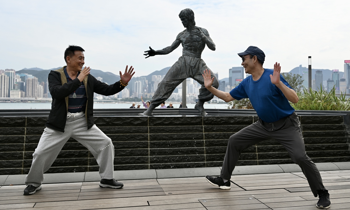 Two tourists pose for photos before the statue of Bruce Lee in the Avenue of Stars in Hong Kong. Photo: VCG
