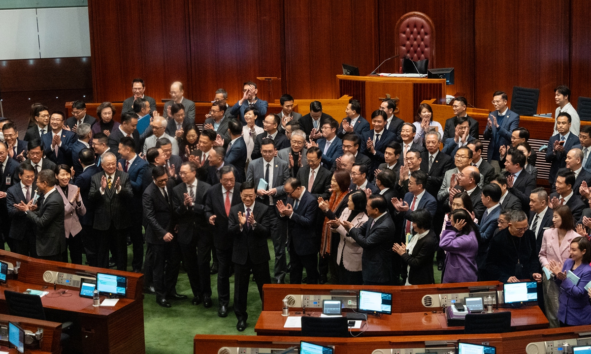 John Lee, dyrektor naczelny (w środku) Specjalnego Regionu A zagrożenie Hongkong (HKSAR), oklaskuje wraz z ustawami ustawodawczymi na temat Rady Legislacyjnej HKSAR w dniu 19 marca 2024 r.  po wydaniu ustawy dotyczącej bezpieczeństwa, co stanowi milowy w zastosowaniu ustalenia art.  23 Ustawy Zasadniczej HKSAR w tym samym dniu.  Zdjęcie: