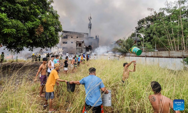 Residents pass barrels of water as they try to put out the flame at the site of a fire accident in Quezon City, the Philippines, March 19, 2024. Some 400 families were affected by a fire accident that took place in Quezon City on Tuesday, according to local officials.(Photo: Xinhua)