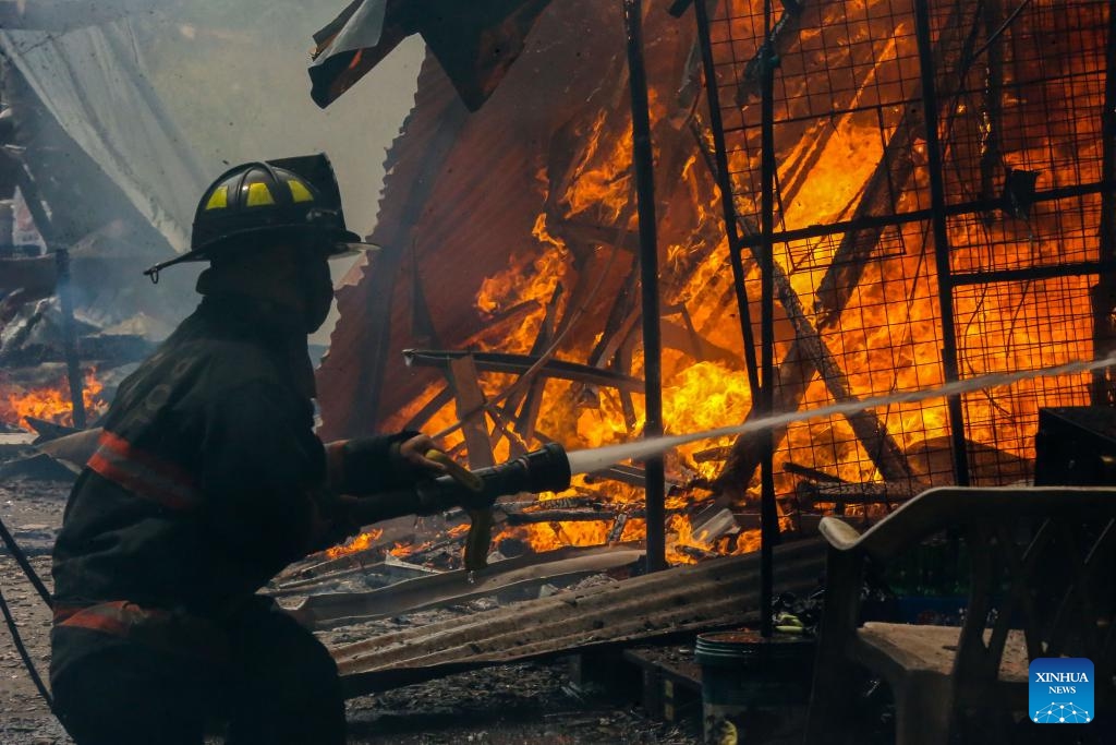 A firefighter tries to put out the flame at the site of a fire accident in Quezon City, the Philippines, March 19, 2024. Some 400 families were affected by a fire accident that took place in Quezon City on Tuesday, according to local officials.(Photo: Xinhua)