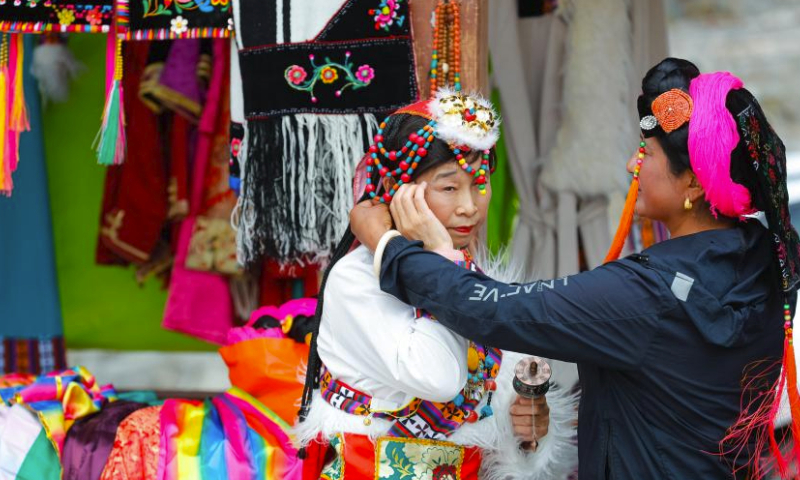A tourist adjusts Tibetan attire before a photo session at a hamlet in Danba County, Tibetan Autonomous Prefecture of Garze, southwest China's Sichuan Province, March 23, 2024. Danba County has rolled out policies to support the development of the homestay industry and accelerate the high-quality development of the cultural tourism industry. (Xinhua/Shen Bohan)