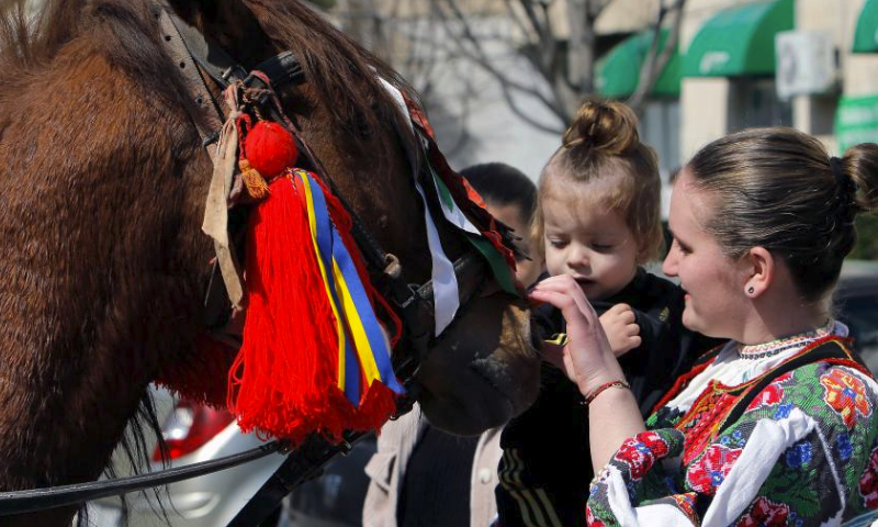 A woman and her child interact with a horse during the celebration of the traditional Tudorita holiday, also known as the Easter of Horses, in Targoviste, 80 km north of Bucharest, Romania, March 23, 2024. Easter of Horses is celebrated by the local Bulgarian community and symbolizes the start of agricultural work in the new year. (Photo by Cristian Cristel/Xinhua)