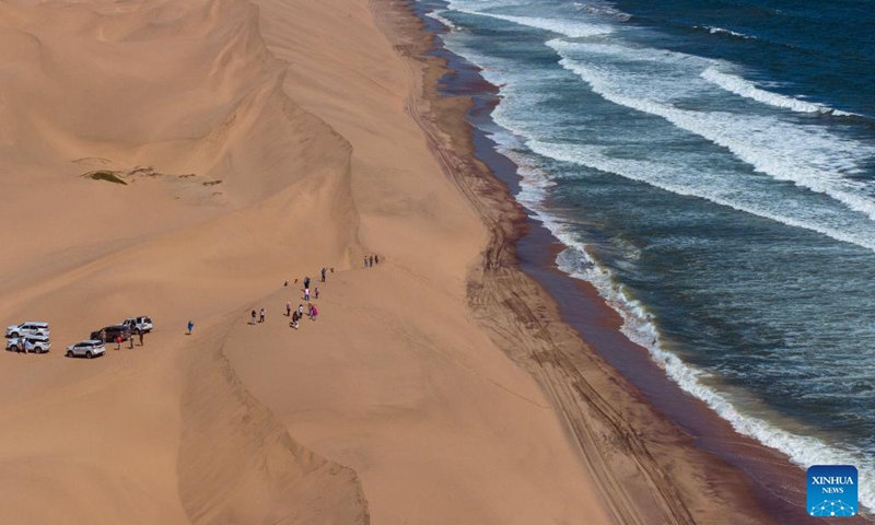 An aerial drone photo taken on March 24, 2024 shows tourists visiting the Sandwich Harbor at Namib-Naukluft National Park in Namibia. In Namibia's Namib-Naukluft National Park, located 400 kilometers from the capital city of Windhoek, there is a scenic spot known as Sandwich Harbor. With its unique half sea and half desert scenery, it attracts tourists from around the world.(Photo: Xinhua)