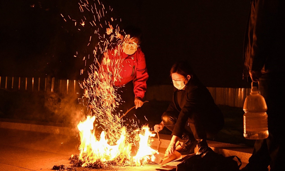 People burn joss paper on a sidewalk on the eve of Qingming Festival in Beijing on April 3, 2021. Photo: VCG