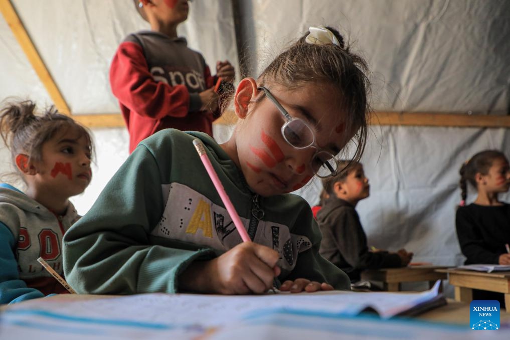 A Palestinian girl studies at a temporary classroom in the southern Gaza Strip city of Rafah, March 27, 2024. The heavy bombardment against Gaza by Israel has resulted in direct hits on 212 schools within the enclave, according to analysis partnered with the United Nations released on Wednesday. Satellite images have shown that at least 53 schools have been completely destroyed since the conflict began on Oct. 7, 2023.(Photo: Xinhua)