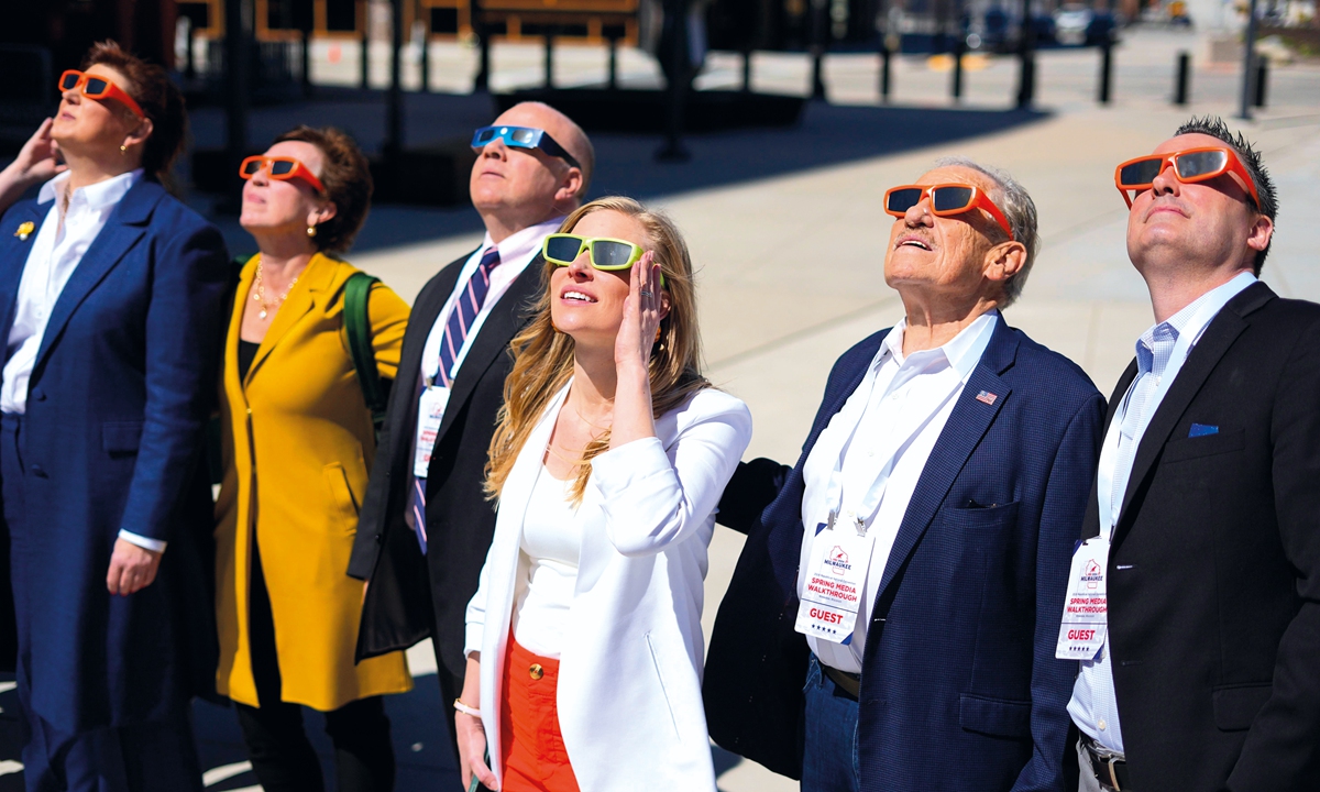 People gather to look up during a solar eclipse outside the Fiserv Forum in Milwaukee, Wisconsin on April 8, 2024. The eclipse was a total solar eclipse visible within a band covering parts of North America, from Mexico to Canada. Photo: VCG