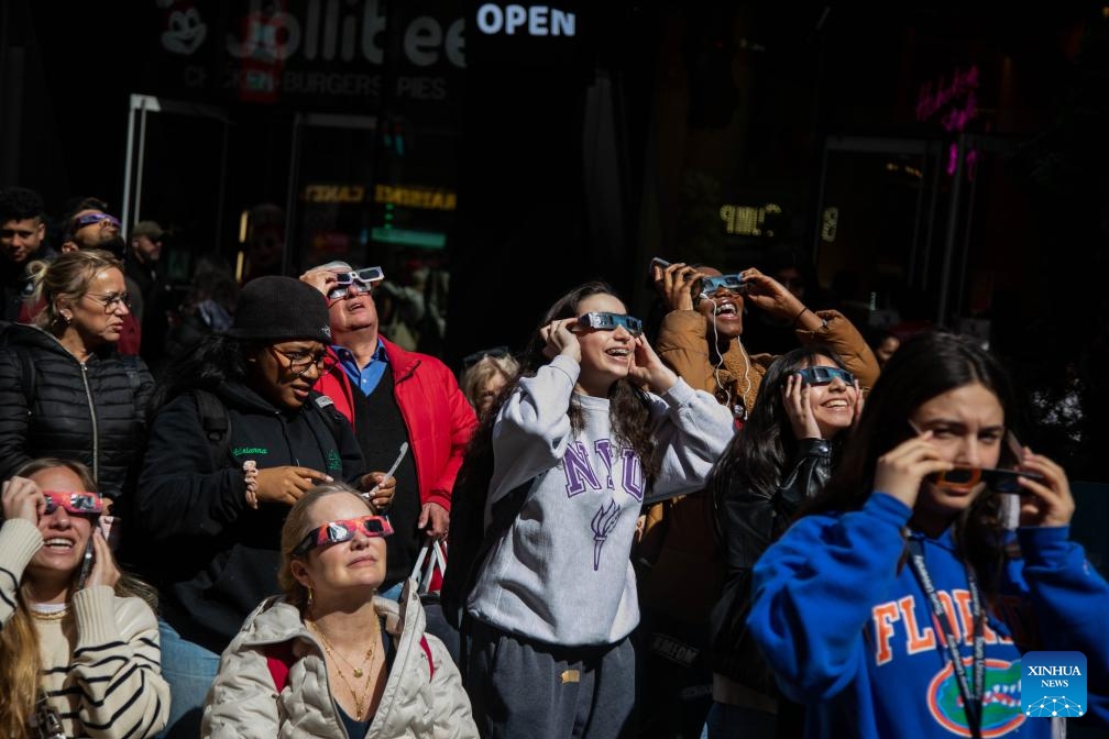 People watch a solar eclipse in the Times Square neighborhood of New York City, the United States, on April 8, 2024. A total solar eclipse was sweeping across North America on Monday, as residents and visitors gathered in different locations on the path of the eclipse to watch and cheer.(Photo: Xinhua)