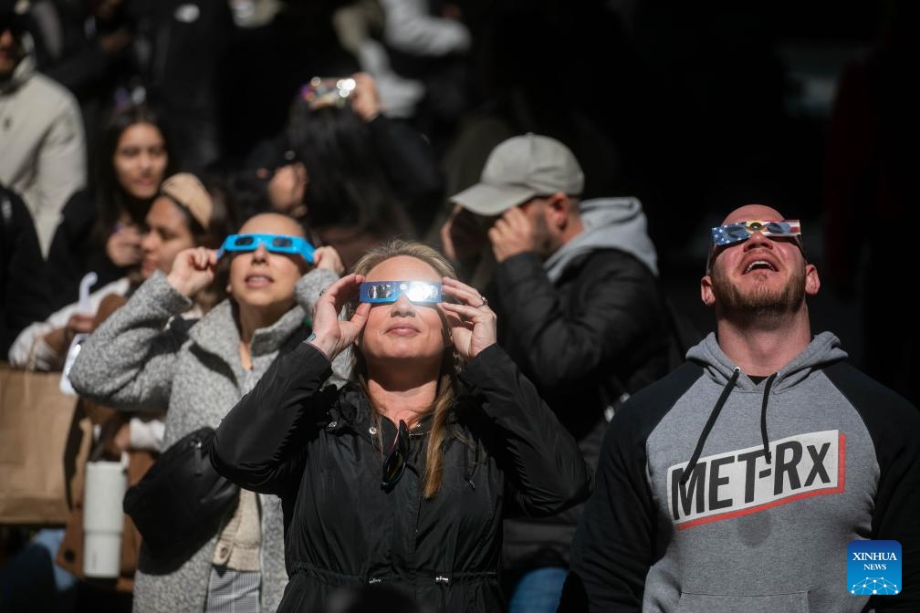 People watch a solar eclipse in the Times Square neighborhood of New York City, the United States, on April 8, 2024. A total solar eclipse was sweeping across North America on Monday, as residents and visitors gathered in different locations on the path of the eclipse to watch and cheer.(Photo: Xinhua)