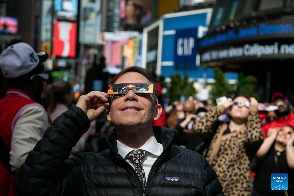 People watch a solar eclipse in the Times Square neighborhood of New York City, the United States, on April 8, 2024. A total solar eclipse was sweeping across North America on Monday, as residents and visitors gathered in different locations on the path of the eclipse to watch and cheer.(Photo: Xinhua)