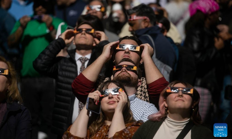 People watch a solar eclipse in the Times Square neighborhood of New York City, the United States, on April 8, 2024. A total solar eclipse was sweeping across North America on Monday, as residents and visitors gathered in different locations on the path of the eclipse to watch and cheer.(Photo: Xinhua)