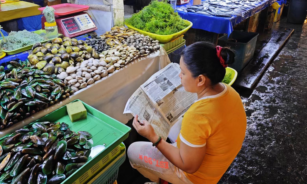 A seafood merchant in Davao, Philippines, reads a newspaper about Philippine Coast Guard operations in the South China Sea on March 25, 2024. Photo: Hu Yuwei/Global Times