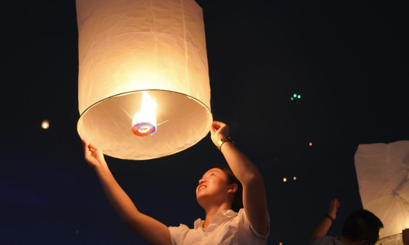 People fly Kongming lanterns, a kind of small hot-air paper balloon, by the Lancang River in Jinghong City, southwest China's Yunnan Province, April 13, 2024, to celebrate the New Year of the calendar of the Dai ethnic group. (Xinhua/Wang Jingyi)