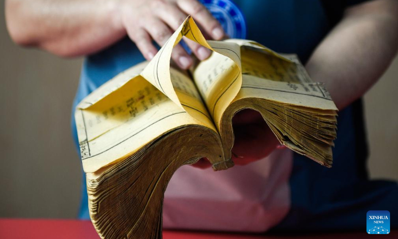 Zhang Qi, a restorer of ancient books in the library of Jilin University, observes the damage of the pages of an ancient book ahead of restoration at the library of Jilin University in Changchun, northeast China's Jilin Province, April 19, 2024. (Xinhua/Xu Chang)
