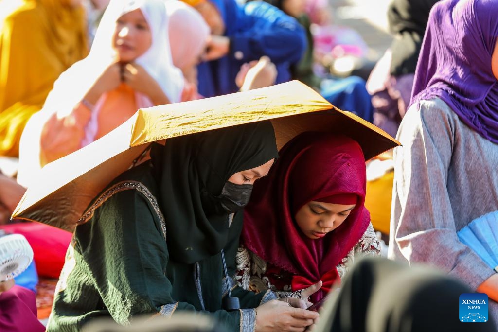 Two women share an umbrella as they attend a prayer in celebration of the Eid al-Fitr in Quezon City, the Philippines, on April 10, 2024.(Photo: Xinhua)