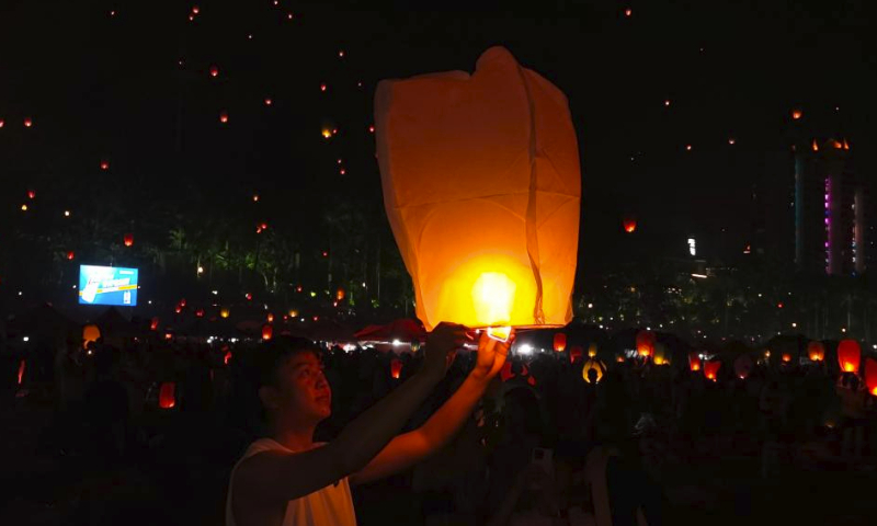 People fly Kongming lanterns, a kind of small hot-air paper balloon, by the Lancang River in Jinghong City, southwest China's Yunnan Province, April 13, 2024, to celebrate the New Year of the calendar of the Dai ethnic group. (Xinhua/Wang Jingyi)