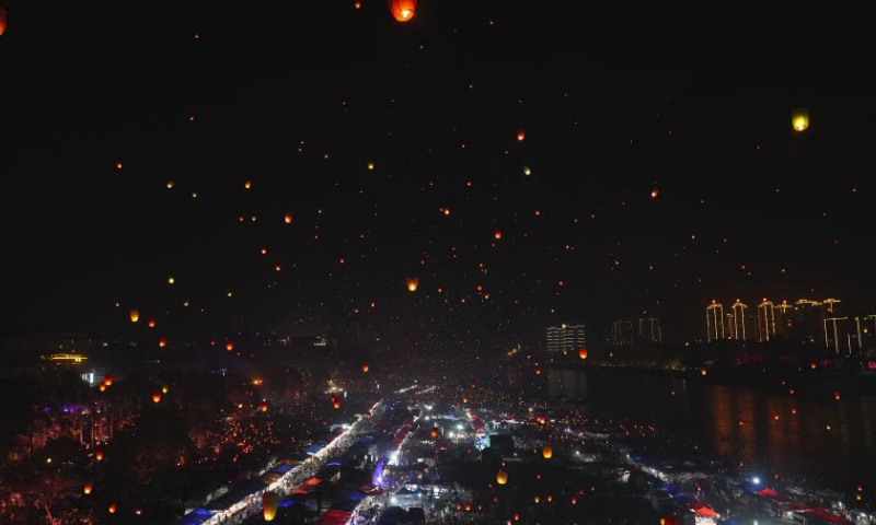 People fly Kongming lanterns, a kind of small hot-air paper balloon, by the Lancang River in Jinghong City, southwest China's Yunnan Province, April 13, 2024, to celebrate the New Year of the calendar of the Dai ethnic group. (Xinhua/Wang Jingyi)