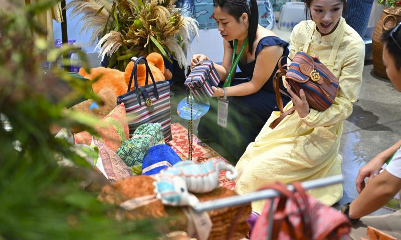 Visitors select products designed with elements of Li ethnic group at the fourth China International Consumer Products Expo (CICPE) in Haikou, capital city of south China's Hainan Province, April 13, 2024. A batch of domestic brands have attracted a lot of visitors at the expo. (Xinhua/Guo Cheng)