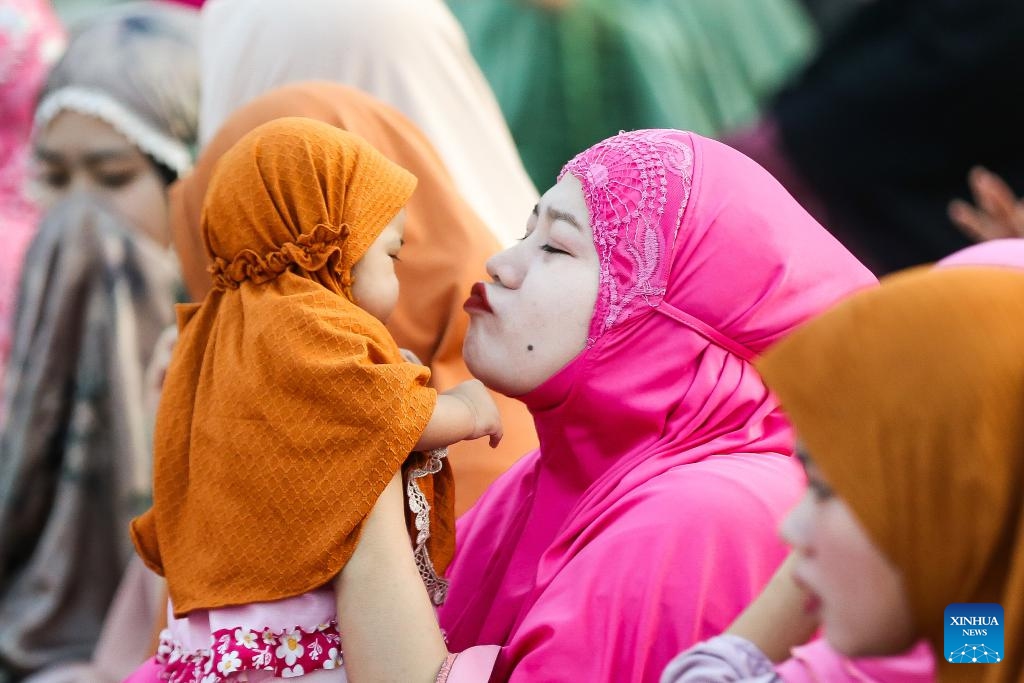 A mother kisses her daughter as they attend a prayer in celebration of the Eid al-Fitr in Quezon City, the Philippines, on April 10, 2024.(Photo: Xinhua)