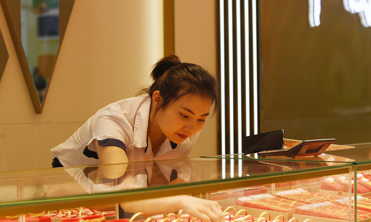 A sales manager arranges gold jewelry inside a shop in Renhuai, Southwest China's Guizhou Province on April 18, 2024. The continuous rise of global gold prices has warmed up gold sales in China. In 2023, China's gold jewelry consumption hit 706.48 tons, a year-on-year increase of 7.97 percent, data showed. Photo: cnsphoto