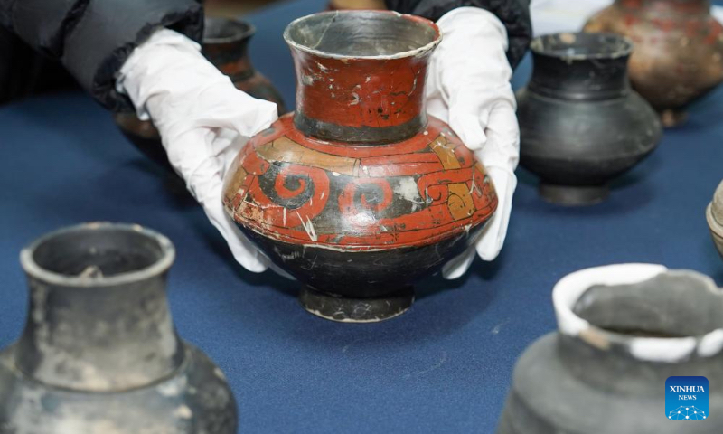 This photo taken on April 8, 2024 shows a staff member of Nanjing Museum arranging pottery pots unearthed at Sidun Site in Changzhou, east China's Jiangsu Province. (Xinhua/Li Bo)