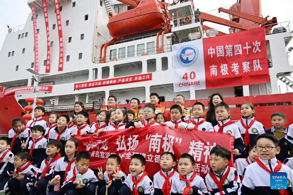 Students and members of the expedition team pose for a group photo in front of the icebreaker Xuelong at a port in Qingdao, east China's Shandong Province, April 10, 2024. China's research icebreaker Xuelong on Wednesday arrived at a port in Qingdao after completing its latest Antarctic expedition and it will host a three-day open house to the public.(Photo: Xinhua)