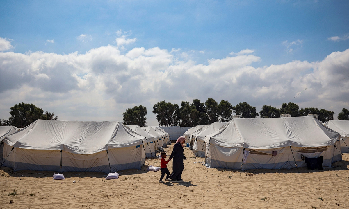 A woman and child walk past tents at a camp for displaced Palestinians in Rafah, in the southern Gaza Strip, on April 14, 2024. Photo: VCG