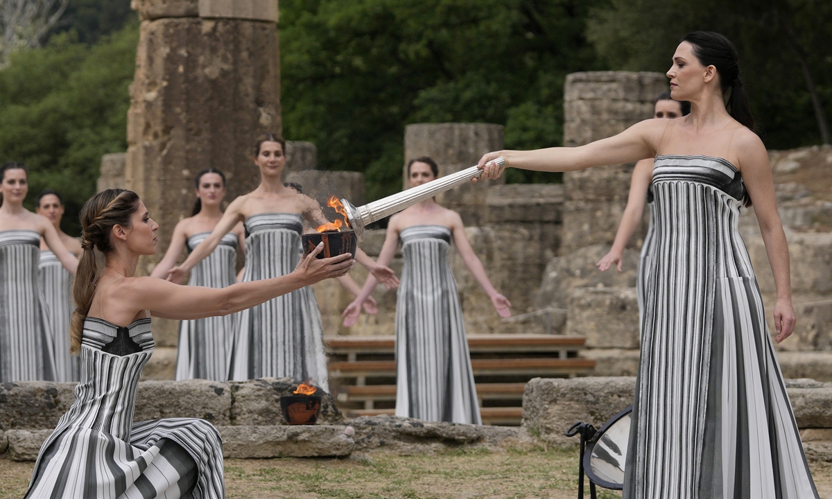 Actress Mary Mina (right), playing the role of high priestess, lights a torch during the official ceremony of the flame lighting for the Paris Olympics, at the Ancient Olympia site, Greece, on April 16, 2024. The flame will be carried through Greece for 11 days before being handed over to Paris organizers on April 26. Photo: VCG
