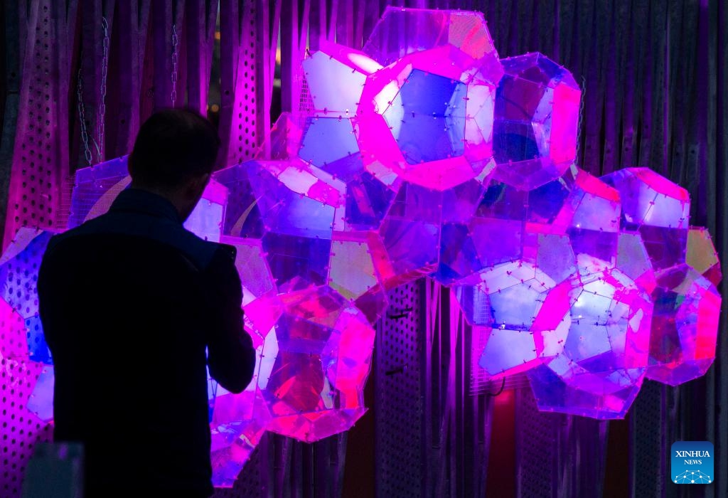 A man takes photos of a light art installation during the Lumiere: The Art of Light exhibition in Toronto, Canada, on April 15, 2024. Featuring 17 light installations created by local artists, the outdoor light-based art exhibition is held here from March 12 to April 20.(Photo: Xinhua)