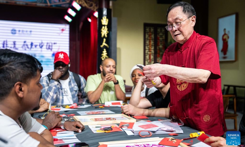 An intangible cultural heritage inheritor (1st R) teaches international students paper-cutting techniques at the Museum of Intangible Cultural Heritage of Changsha in central China's Hunan Province, April 18, 2024.(Photo: Xinhua)