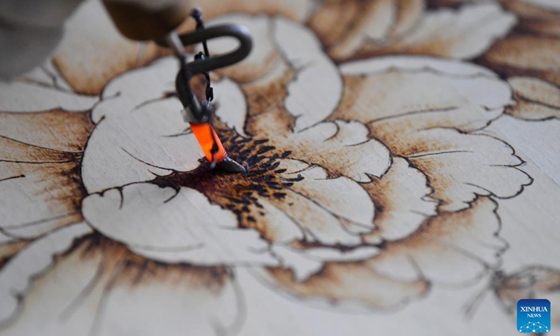 Li Zhe makes a wooden pyrography at a studio of Nanyang Pyrography Factory in Nanyang City, central China's Henan Province, March 15, 2024.