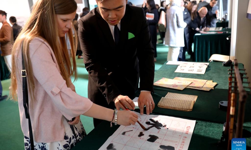 A woman learns Chinese calligraphy at an event named Evolution of Chinese Characters in London, Britain, April 20, 2024. A special exhibition of Chinese characters was launched here on Saturday to celebrate the Chinese Language Day of the United Nations (UN). (Xinhua/Li Ying)