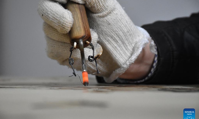 Li Zhe makes a wooden pyrography at a studio of Nanyang Pyrography Factory in Nanyang City, central China's Henan Province, March 15, 2024.