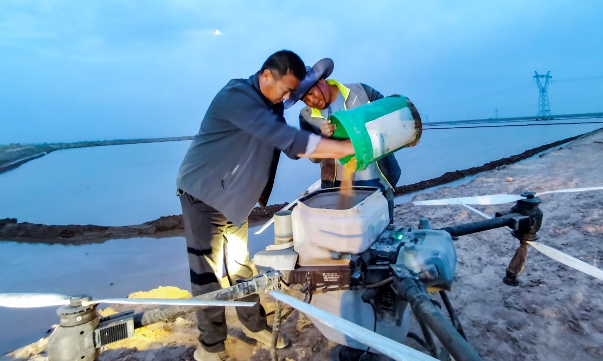 Farmers put seeds on drones. Photo: Zhou Peng of Xinjiang Daily