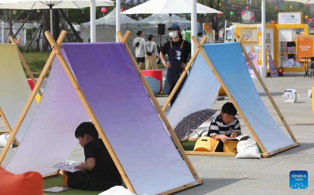 People read at Seoul Plaza in Seoul, South Korea, April 21, 2024. Seoul Outdoor Library opens to the public on April 18. The Seoul city government has set up lending services counters, beanbags, leisure chairs and other facilities in Seoul Plaza, Gwanghwamun Plaza and Cheonggyecheon Stream to encourage citizens and tourists to enjoy reading outdoors. 2024 Seoul Outdoor Library will remain open until November 10.(Photo: Xinhua)